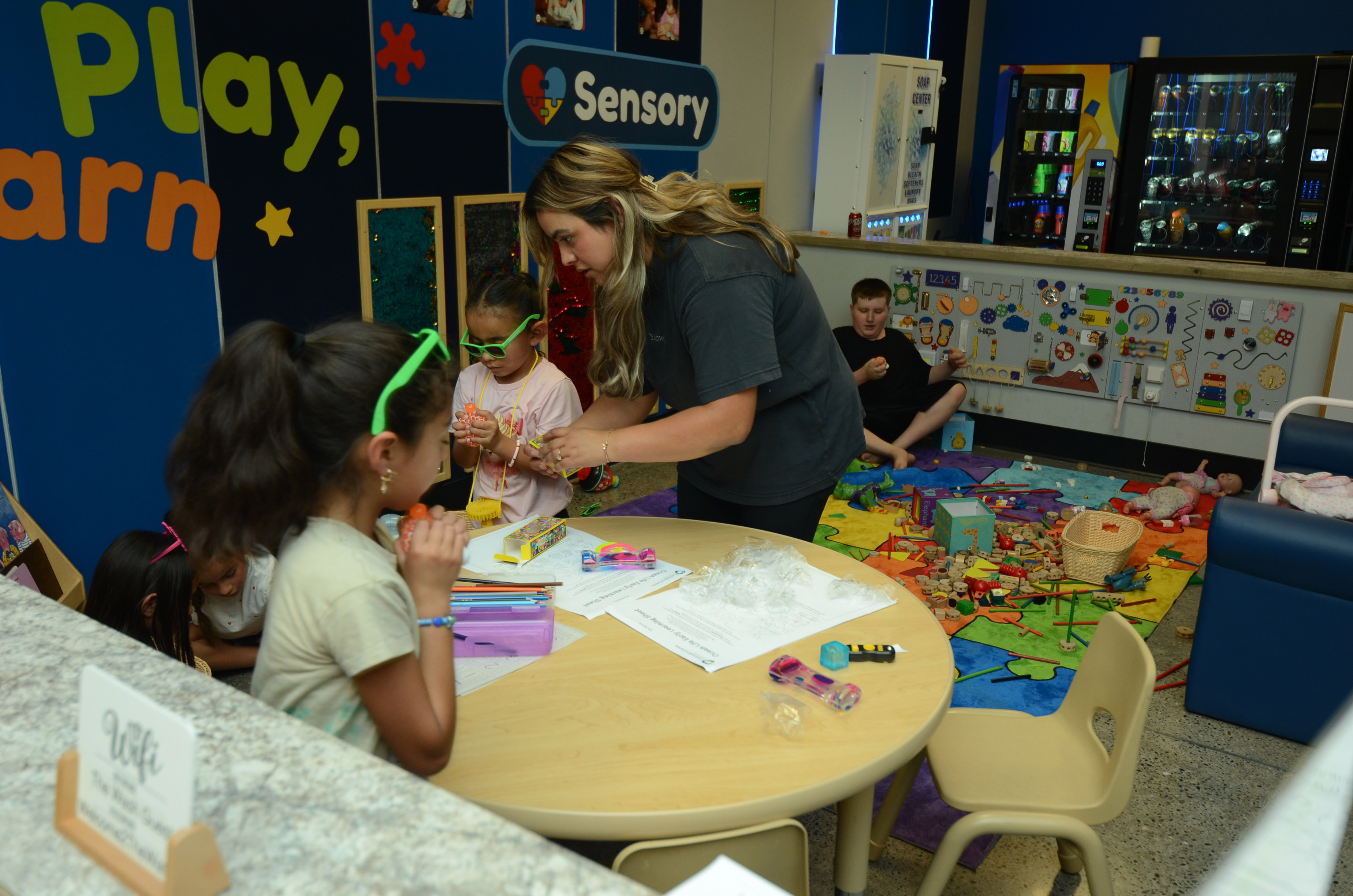 Children and an adult sharing an activity in the Read Play Learn corner during Free Laundry Day