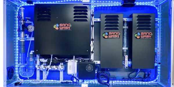 SAN-O-WASH ozone equipment with three black units, piping, and a blue-lit enclosure
